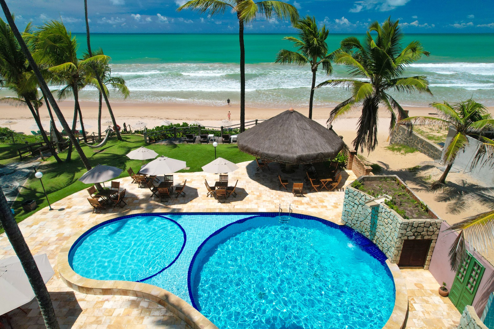 Piscina da pousada vista do alto com o mar ao fundo