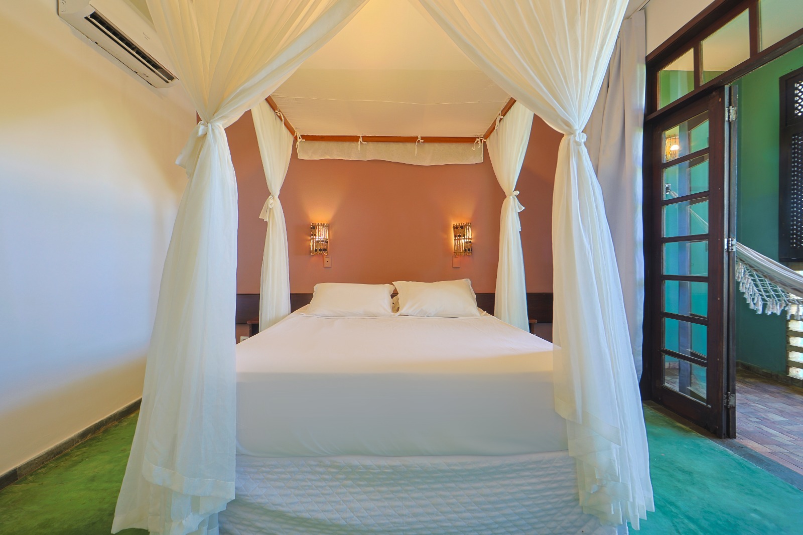 Cama de casal com dossel e cortinas brancas no Quarto Vista Mar